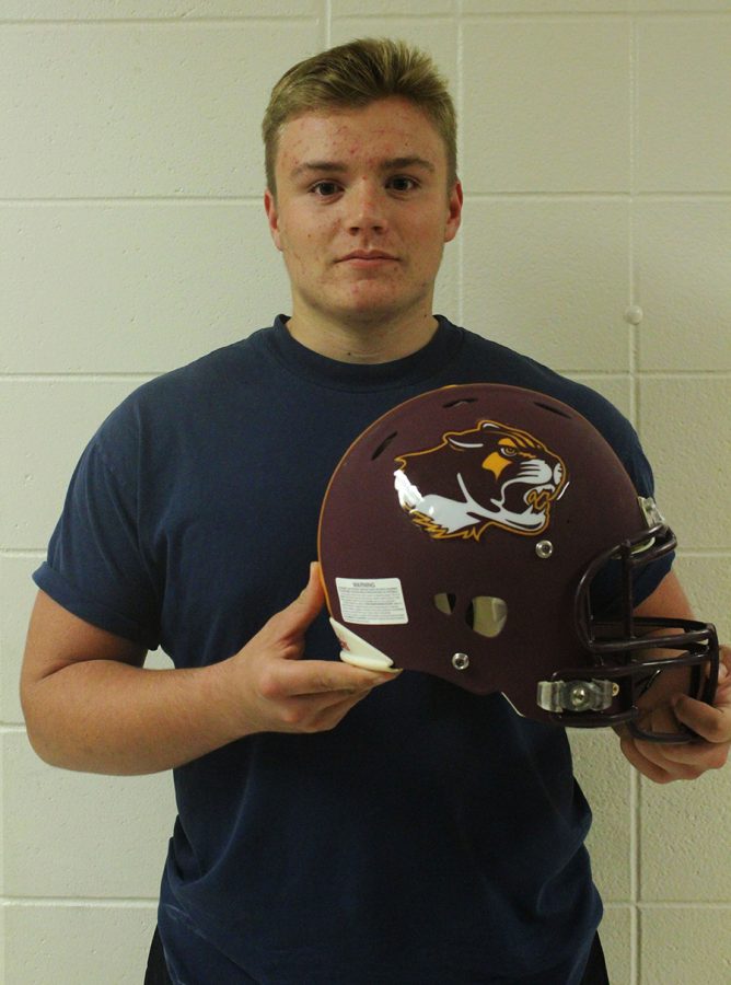 Connor Smith, junior, stares into the camera as he poses with a North Cougars football helmet. (Photo by Frances Sheets)
