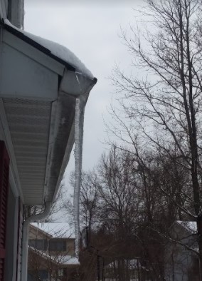 A large icicle hanging from a gutter.