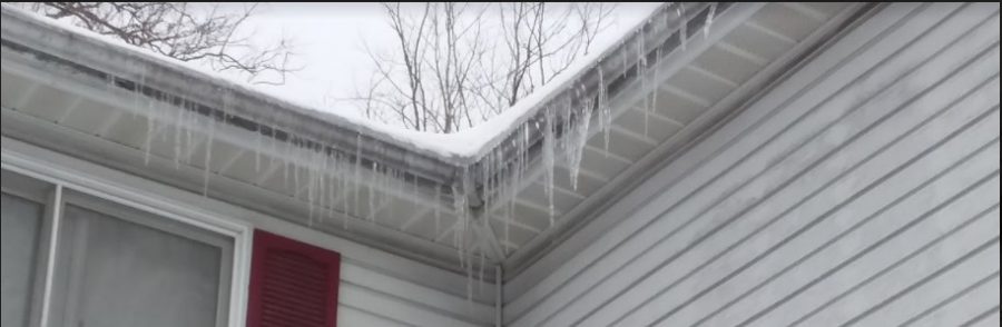 Many small icicles hanging from the roof of a house.